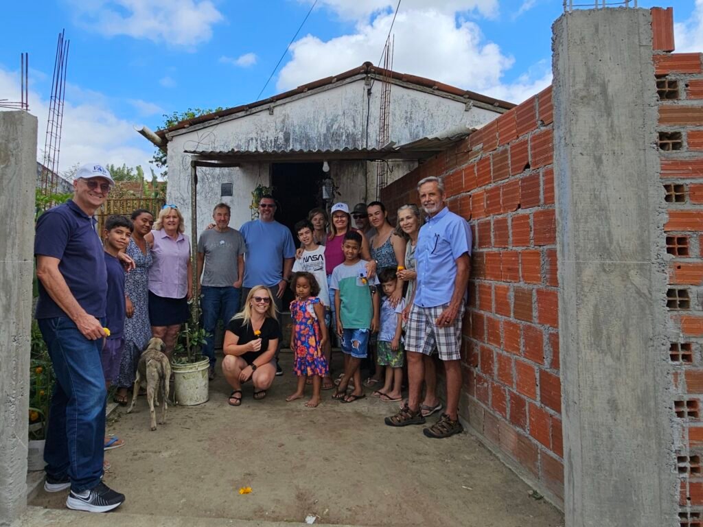 Group of men, women and children posing outside a small home in Queimadas, Brazil