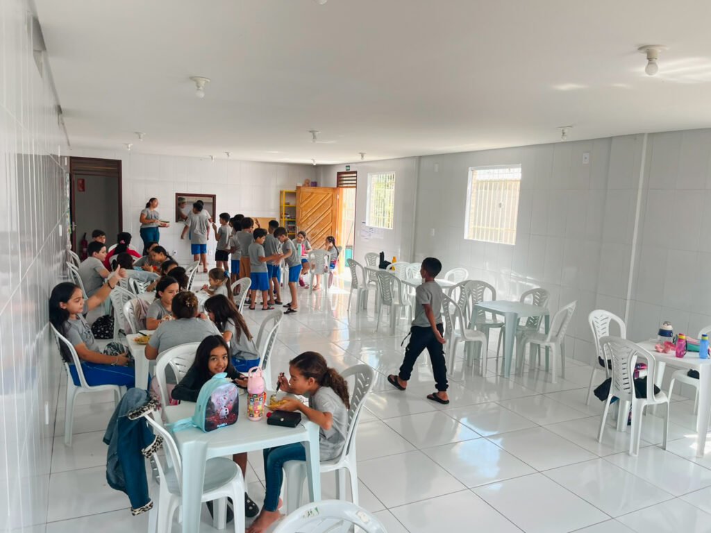lots of kids in a white room with white chairs and tables wearing FAD gray tshirts