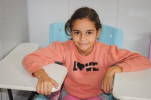 Young girl smiling at camera in a pink sweatshirt