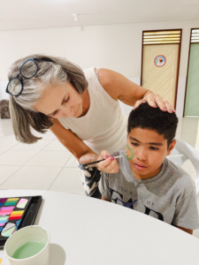 boy wearing gray FAD tshirt getting his face painted by an older woman