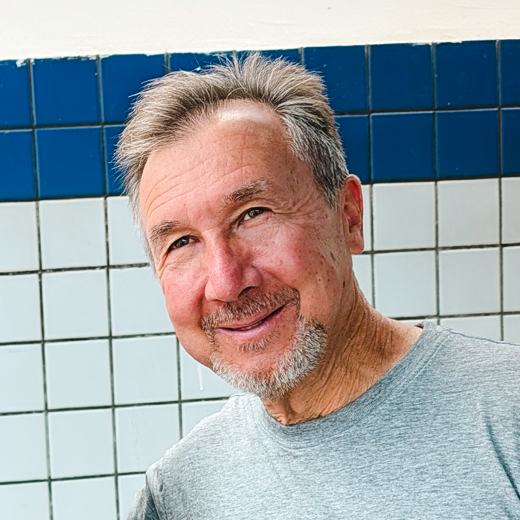 Man smiling in front of tiled wall