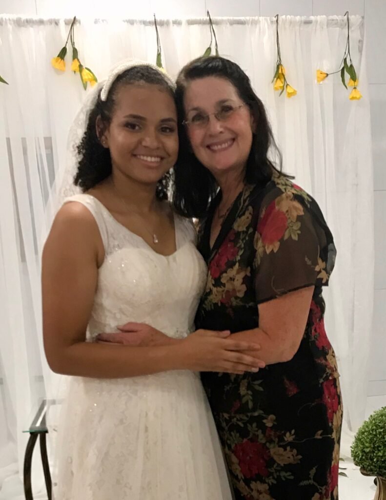 A woman posing with a bride on her wedding day