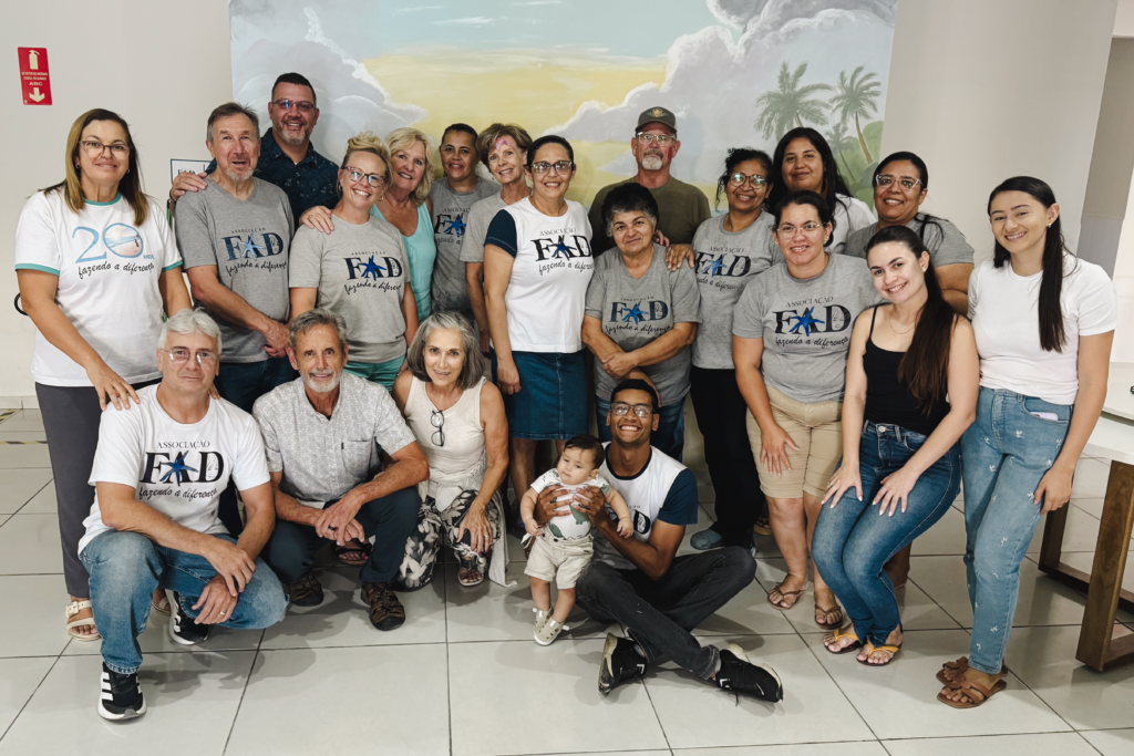 Big group of people standing in front of a wall with a mural at the FAD center, smiling