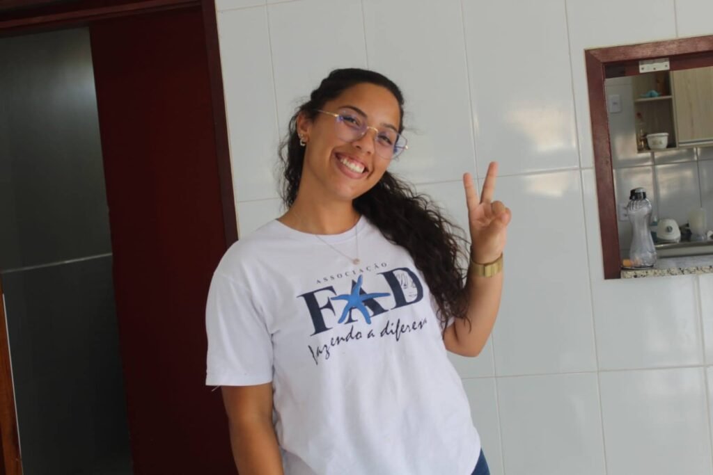 Young woman in FAD t-shirt posing with peace sign fingers and smiling